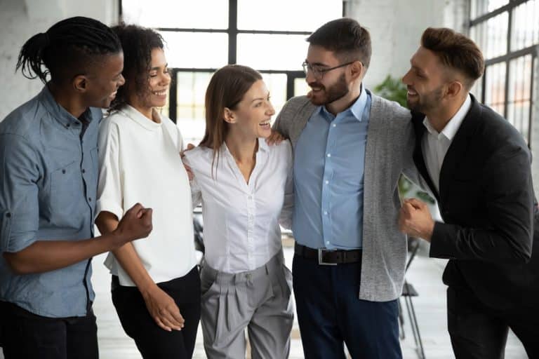 Groupe de collègues souriants se félicitant et partageant un moment de convivialité au travail, symbolisant la cohésion d’équipe et le bien-être au sein de l’entreprise.