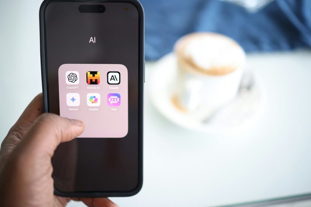 Un smartphone tenu en main affiche plusieurs applications d’intelligence artificielle générative, comme ChatGPT, Gemini et Mistral, illustrant la place croissante de l’intelligence artificielle et travail — Photo de Solen Feyissa sur Unsplash.